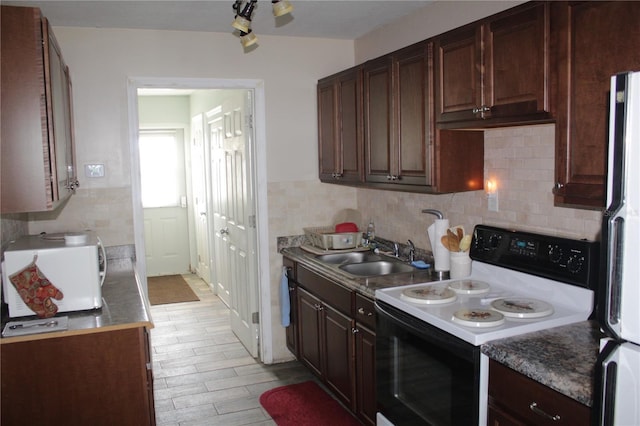 kitchen with tasteful backsplash, sink, dark brown cabinetry, white appliances, and light hardwood / wood-style flooring