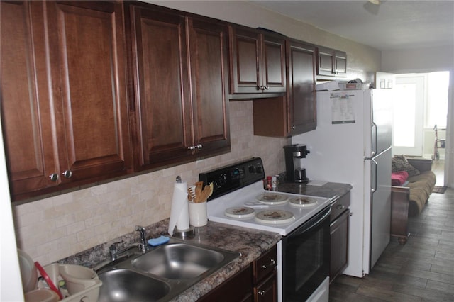 kitchen featuring dark stone counters, white appliances, sink, dark hardwood / wood-style floors, and backsplash