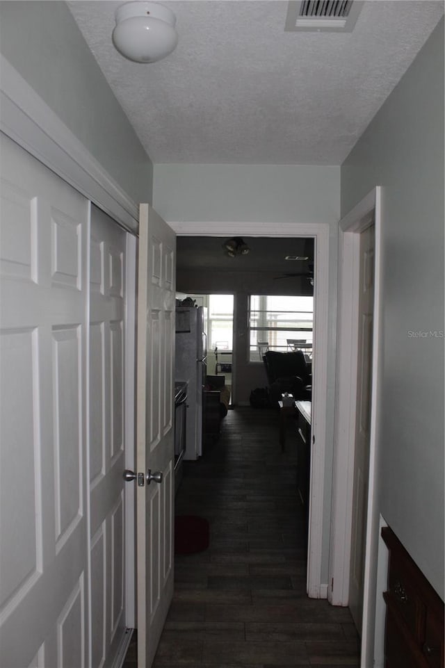 corridor featuring a textured ceiling and dark hardwood / wood-style flooring