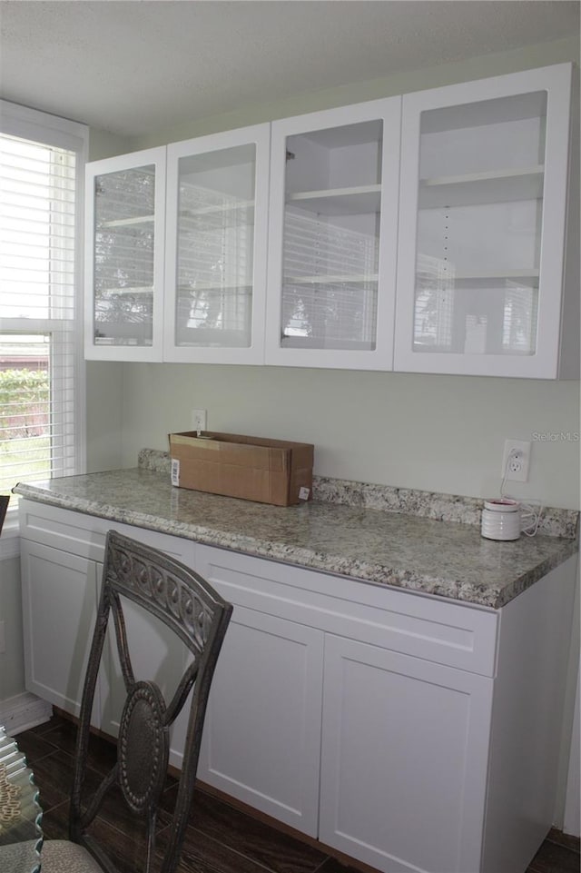 bar with dark wood-type flooring, light stone countertops, and white cabinetry