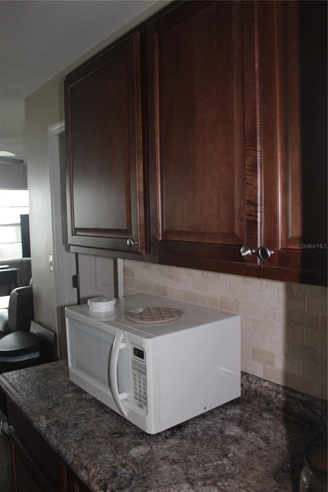 kitchen with dark brown cabinetry, stone counters, and decorative backsplash