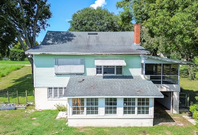 rear view of property with a lawn and a sunroom