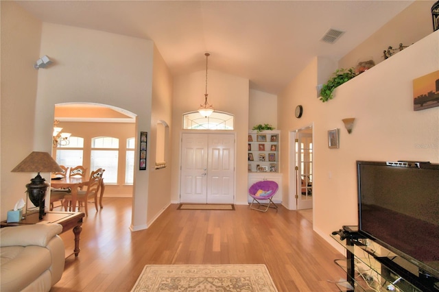 foyer entrance featuring high vaulted ceiling, a chandelier, and light hardwood / wood-style floors