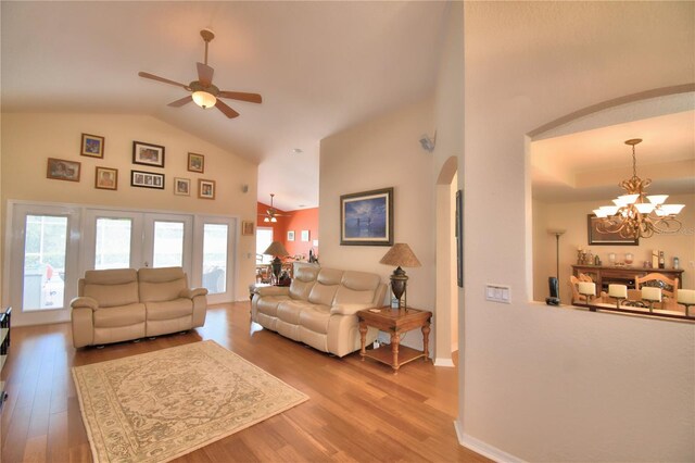 living room featuring ceiling fan with notable chandelier, hardwood / wood-style flooring, and high vaulted ceiling