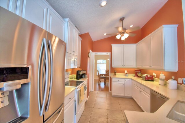 kitchen featuring ceiling fan, white cabinets, stainless steel appliances, and vaulted ceiling