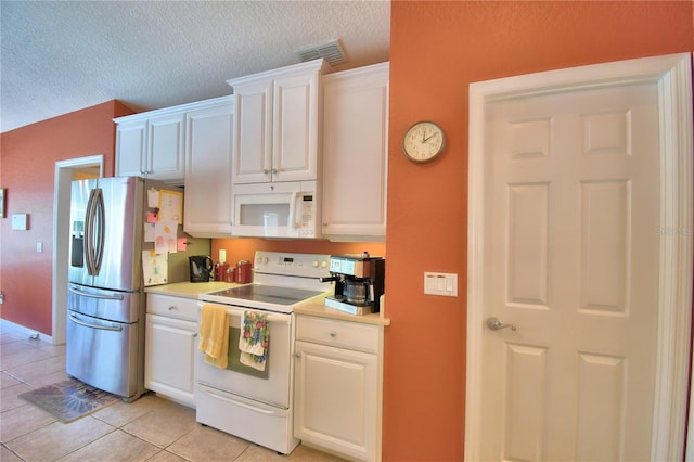 kitchen with white appliances, a textured ceiling, light tile patterned floors, and white cabinetry