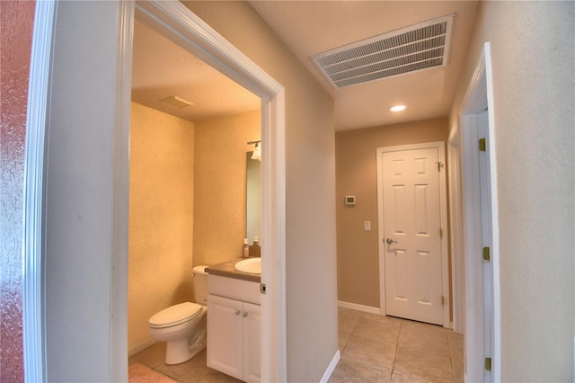 bathroom with toilet, vanity, and tile patterned flooring