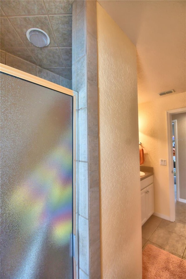 interior space featuring tile patterned floors, walk in shower, and vanity