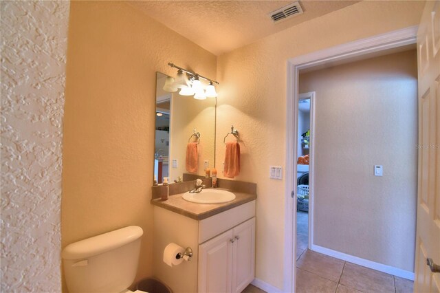 bathroom featuring a textured ceiling, toilet, tile patterned floors, and vanity