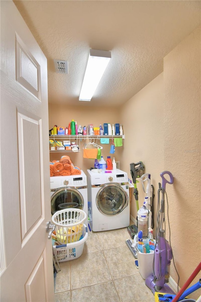 washroom with light tile patterned floors, a textured ceiling, and washer and dryer