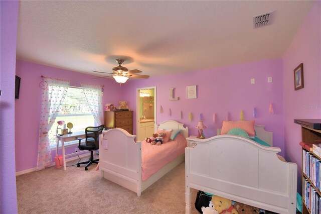 bedroom featuring ensuite bathroom, light colored carpet, and ceiling fan