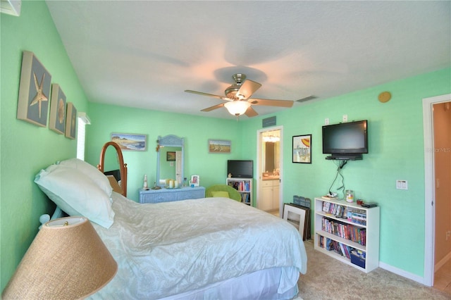 bedroom featuring ceiling fan, ensuite bathroom, and light colored carpet