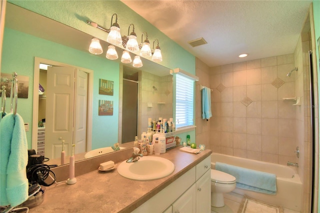 full bathroom featuring a textured ceiling, toilet, tile patterned floors, tiled shower / bath, and vanity