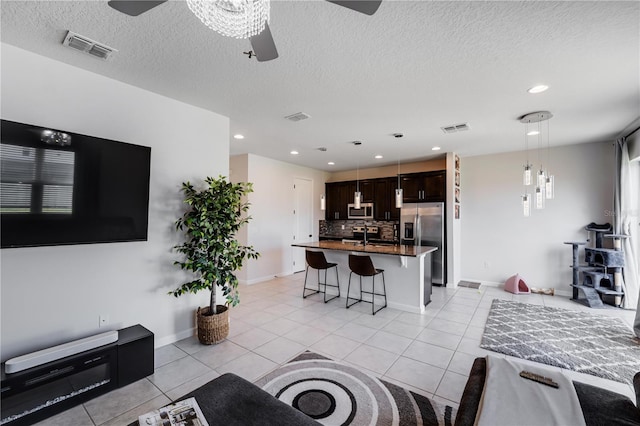 tiled living room with a textured ceiling and ceiling fan