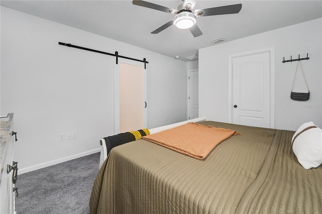 carpeted bedroom with ceiling fan and a barn door