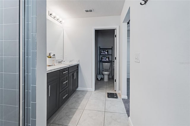 bathroom featuring a textured ceiling, toilet, tile patterned floors, and double sink vanity