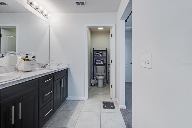 bathroom with double vanity, tile patterned flooring, toilet, and a textured ceiling