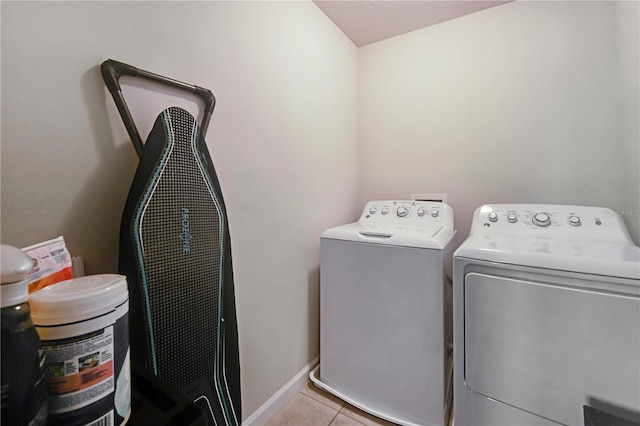 clothes washing area featuring light tile patterned flooring and washer and dryer