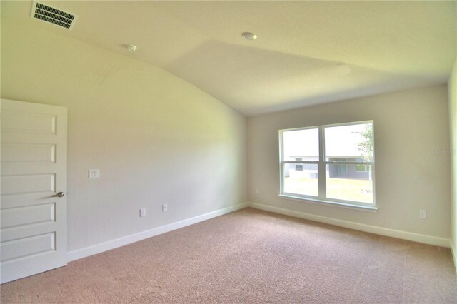 carpeted empty room with vaulted ceiling