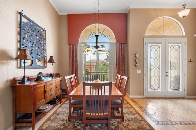 tiled dining room featuring french doors, crown molding, and an inviting chandelier