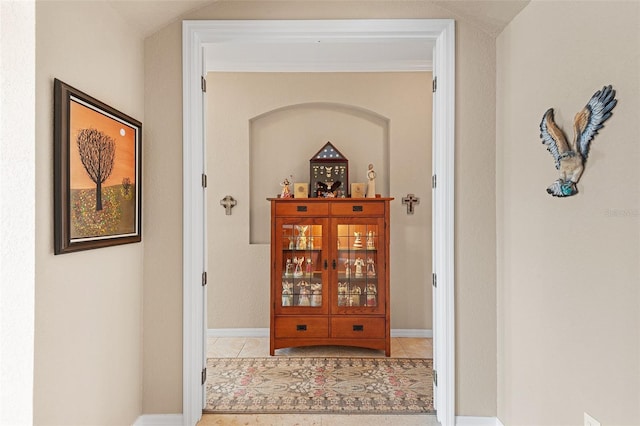 corridor with light tile patterned floors and ornamental molding