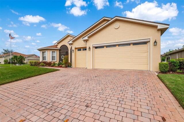 4496 Strathmore Dr, Lake Wales, FL 33859 - view of front of house featuring stucco siding, decorative driveway, a front yard, and an attached garage