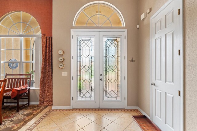 4496 Strathmore Dr, Lake Wales, FL 33859 - entrance foyer with french doors, healthy amount of natural light, tile patterned floors, baseboards, and a towering ceiling