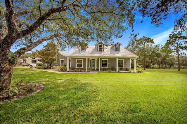 cape cod house with covered porch, metal roof, and a front yard