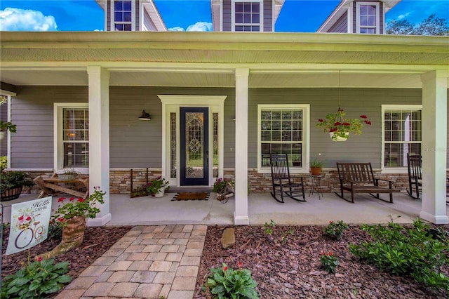 doorway to property featuring stone siding and covered porch