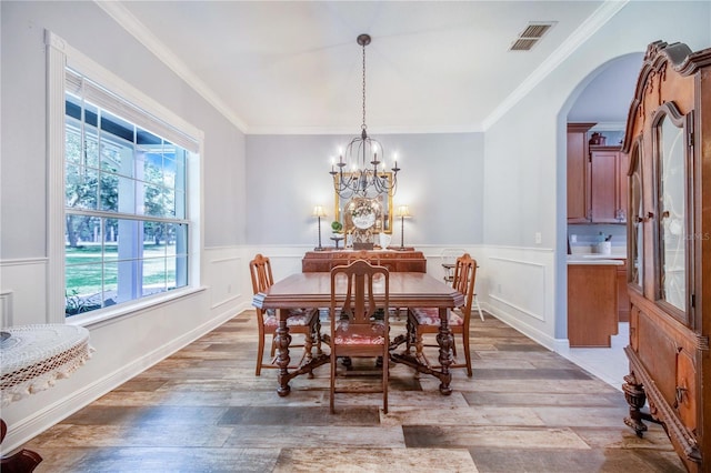 dining area with a notable chandelier, hardwood / wood-style floors, and ornamental molding