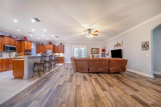 living room with crown molding, light wood-type flooring, and ceiling fan