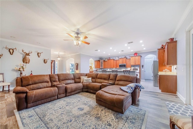 living room featuring crown molding, light wood-type flooring, and ceiling fan