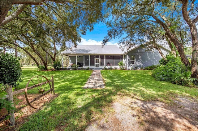 rear view of property featuring metal roof, a yard, and a sunroom