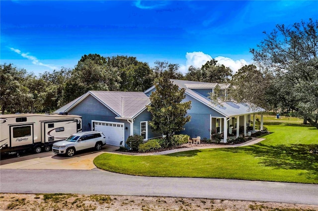 view of front of house featuring metal roof, driveway, a front lawn, and an attached garage