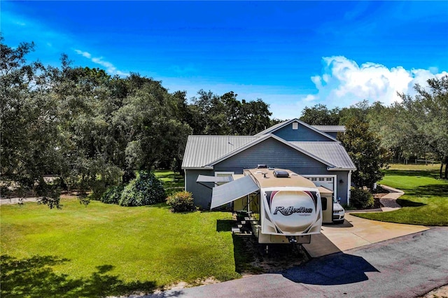 view of front of property with a garage, metal roof, concrete driveway, and a front yard