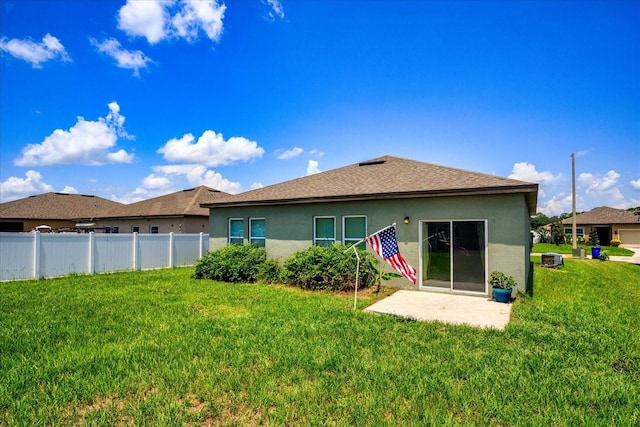 back of house featuring a shingled roof, fence, a lawn, stucco siding, and a patio area