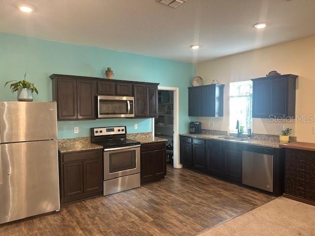 kitchen with dark brown cabinetry, visible vents, dark wood-style flooring, stainless steel appliances, and a sink