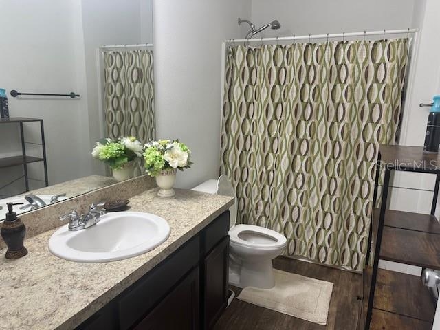 full bathroom with curtained shower, vanity, toilet, and wood finished floors