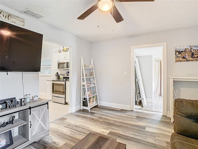 living room with ceiling fan and light hardwood / wood-style flooring