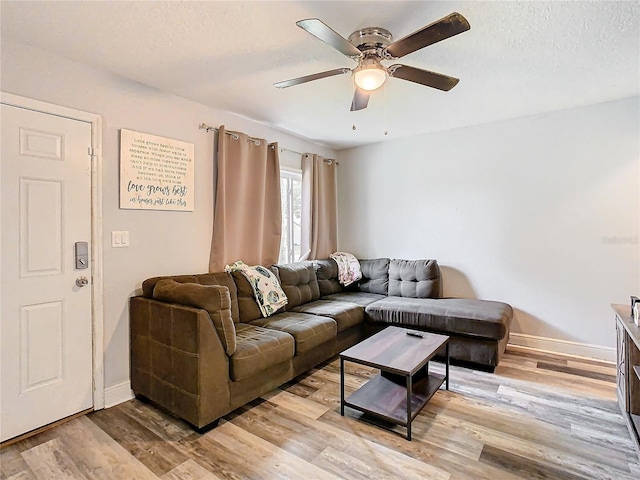 living room with ceiling fan, a textured ceiling, and light hardwood / wood-style flooring