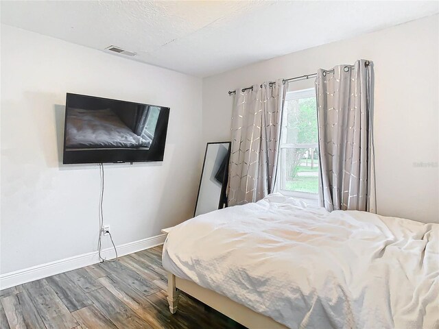 bedroom with hardwood / wood-style floors, a textured ceiling, and access to exterior