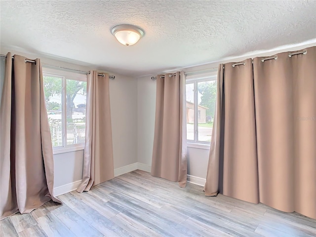 spare room with light hardwood / wood-style floors and a textured ceiling