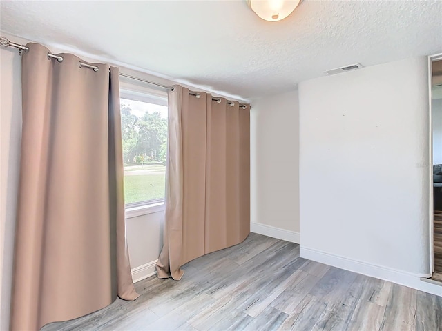 spare room with a textured ceiling and light wood-type flooring