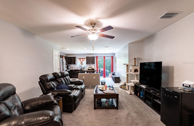 living room featuring light carpet, a textured ceiling, and ceiling fan