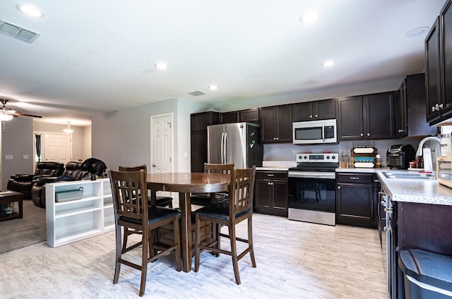 kitchen featuring dark brown cabinets, ceiling fan, stainless steel appliances, light carpet, and sink