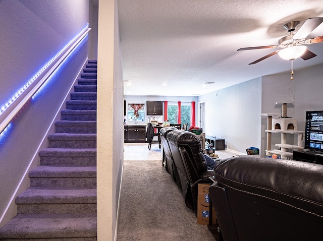 living room featuring light colored carpet, a textured ceiling, and ceiling fan