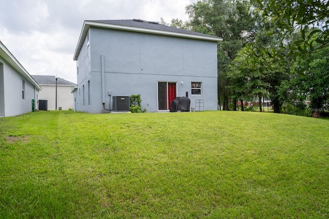 rear view of house with a lawn and central AC unit