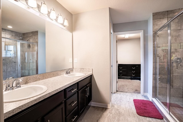 bathroom with a shower with shower door and dual bowl vanity