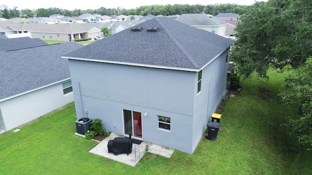 rear view of house with central AC, a patio area, and a lawn