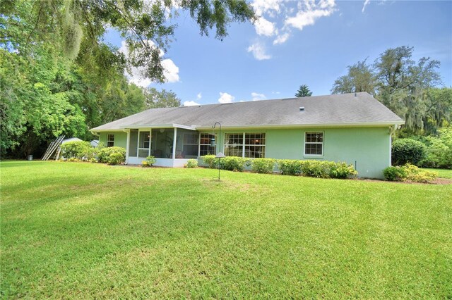 rear view of house featuring a sunroom and a yard